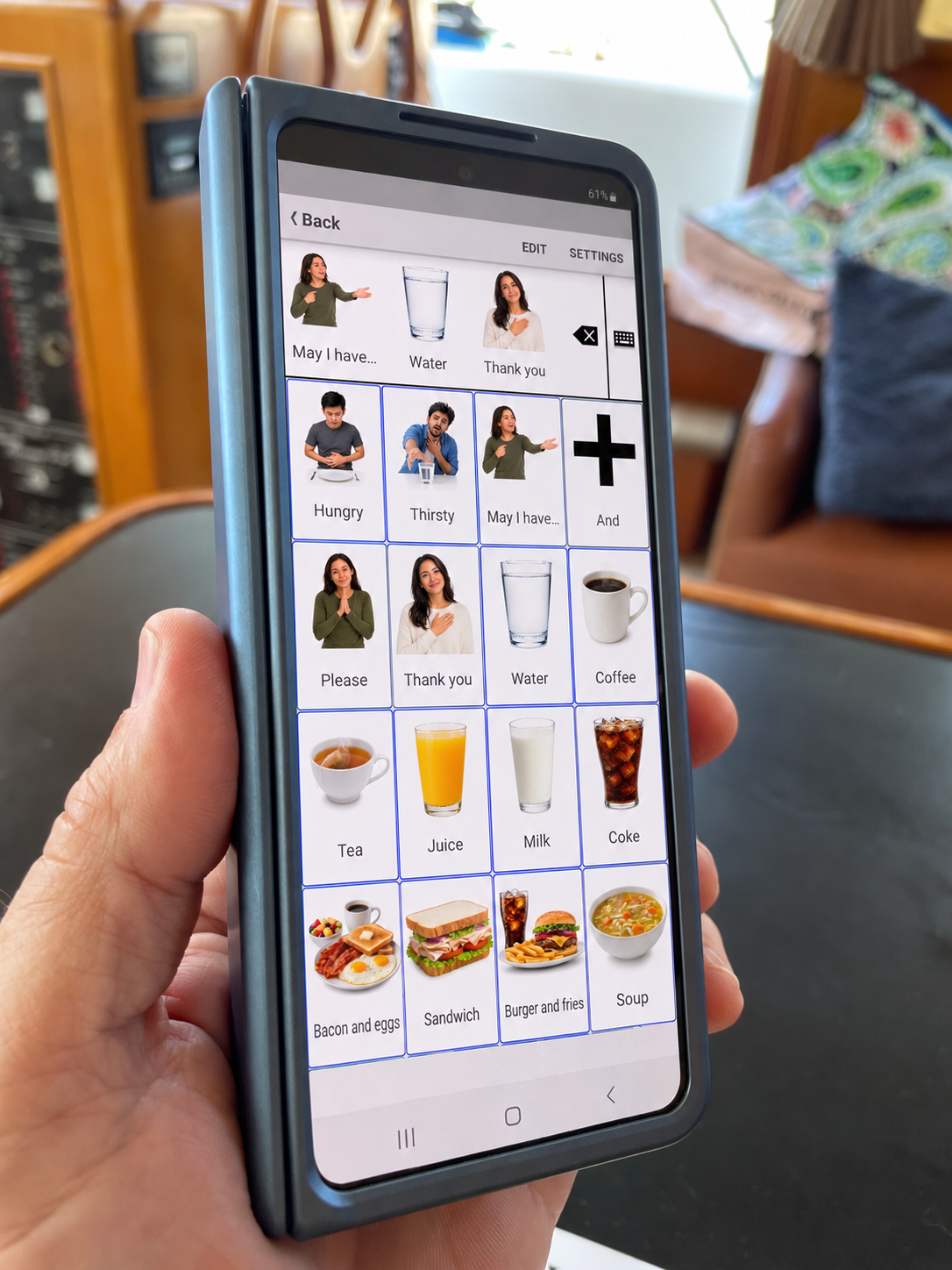 Hand holding the folded Galaxy Z Fold9 Ultra, using TalkTablet PRO photo symbols as a phone-size AAC device